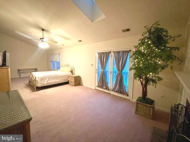 bedroom featuring carpet floors, visible vents, ceiling fan, and lofted ceiling with skylight