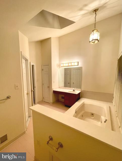 bathroom with a whirlpool tub, a towering ceiling, and vanity