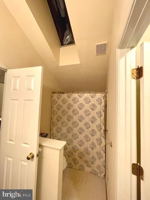 bathroom featuring curtained shower, visible vents, toilet, and tile patterned floors