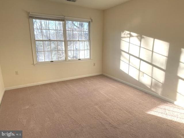 spare room with carpet floors, visible vents, and baseboards