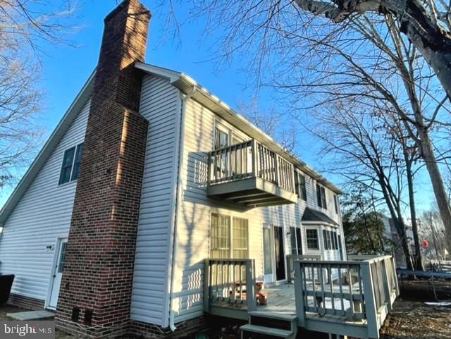 view of home's exterior with a balcony and a chimney