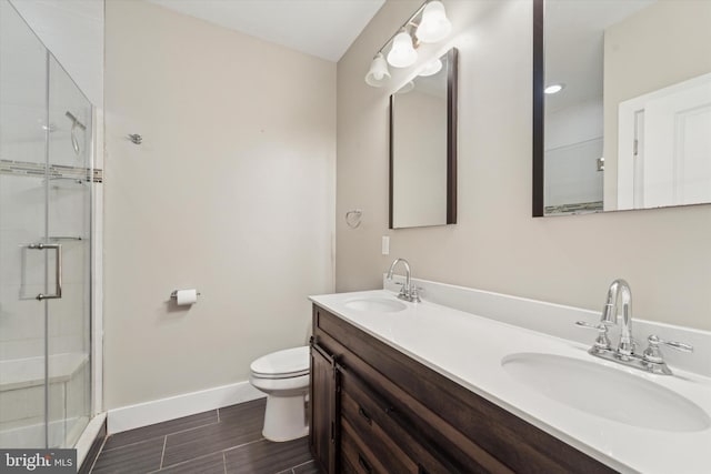 bathroom with a shower with door, vanity, and toilet