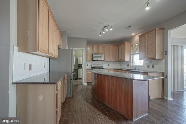 kitchen featuring light brown cabinets, a kitchen island, appliances with stainless steel finishes, and dark wood finished floors