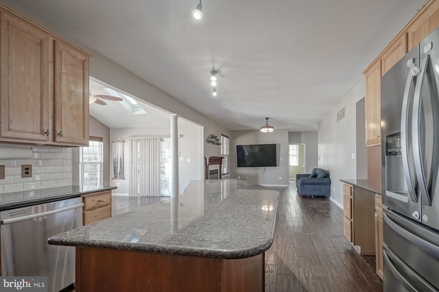 kitchen with open floor plan, appliances with stainless steel finishes, decorative backsplash, and a center island