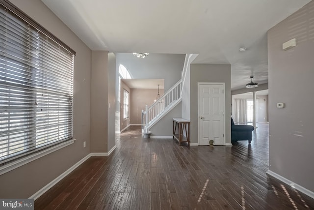 entrance foyer featuring stairs, dark wood-style flooring, a chandelier, and baseboards