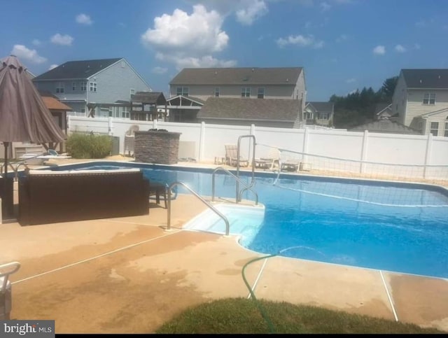 view of swimming pool featuring a patio, a fenced backyard, a residential view, a fenced in pool, and a hot tub