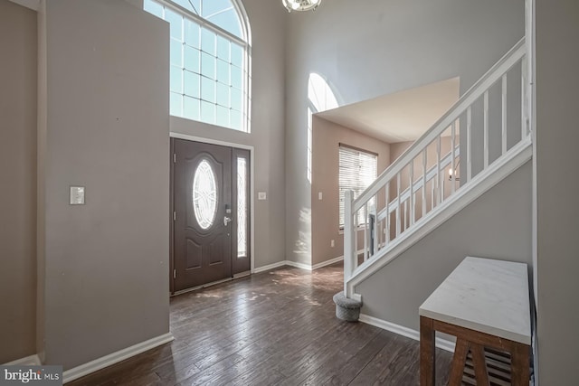 entrance foyer with dark wood-type flooring, a high ceiling, stairway, and baseboards