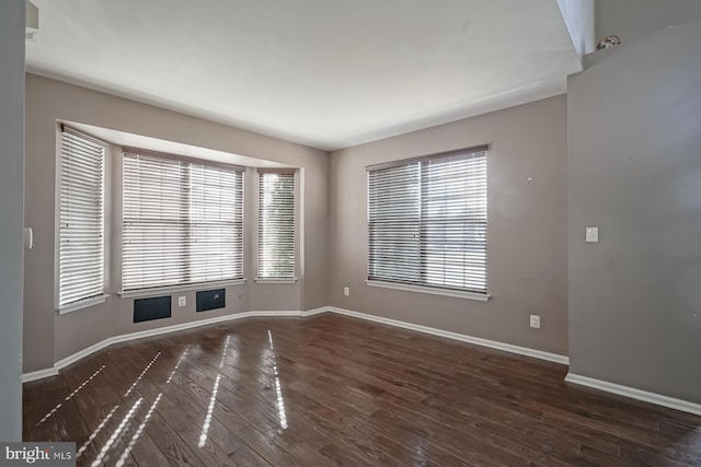 unfurnished room with baseboards and dark wood-style flooring