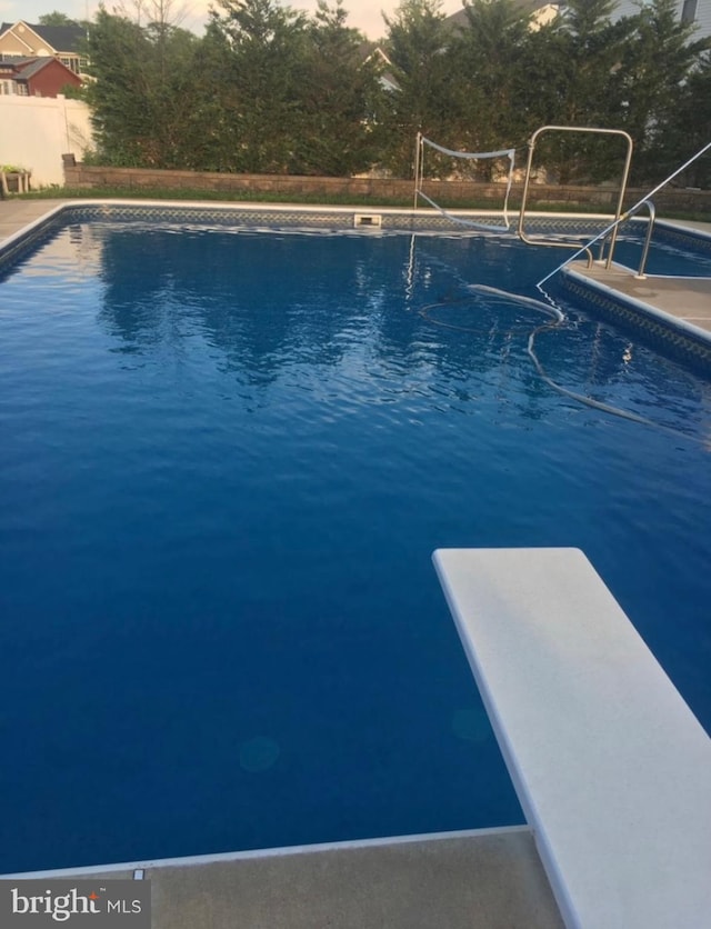 pool at dusk featuring a diving board