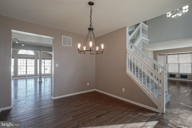 unfurnished room with baseboards, visible vents, dark wood-style floors, stairway, and an inviting chandelier