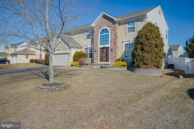 traditional home with driveway, an attached garage, fence, and a front yard