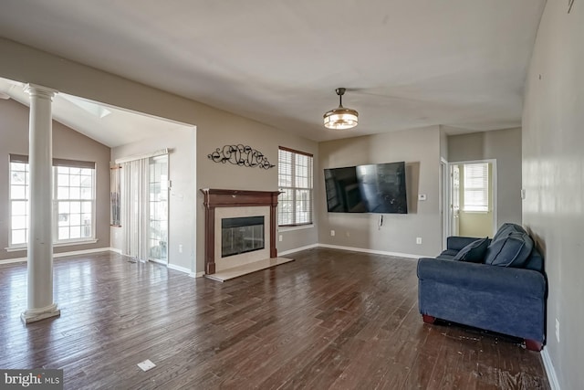 living area featuring a healthy amount of sunlight, dark wood finished floors, a high end fireplace, and ornate columns