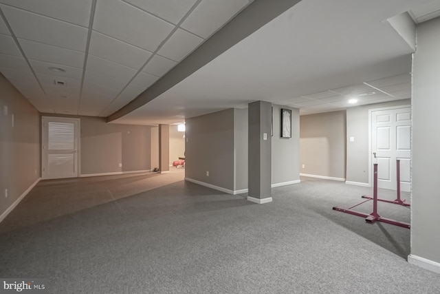 finished basement featuring a paneled ceiling and baseboards