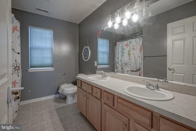 bathroom with toilet, double vanity, a sink, and visible vents