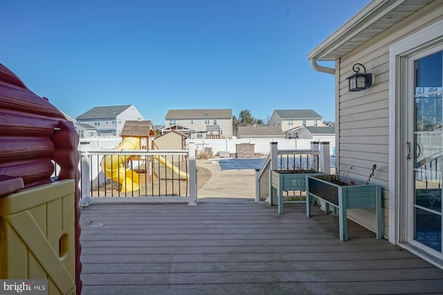 wooden terrace featuring a fenced backyard, a residential view, and a playground