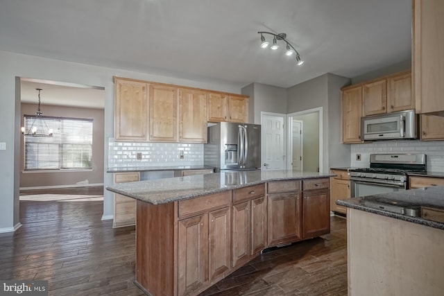 kitchen with hanging light fixtures, a kitchen island, dark stone counters, and stainless steel appliances