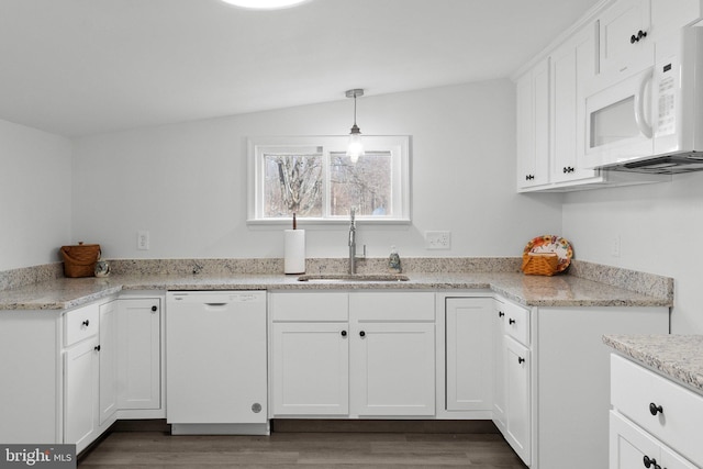 kitchen featuring white appliances, sink, hanging light fixtures, and white cabinets