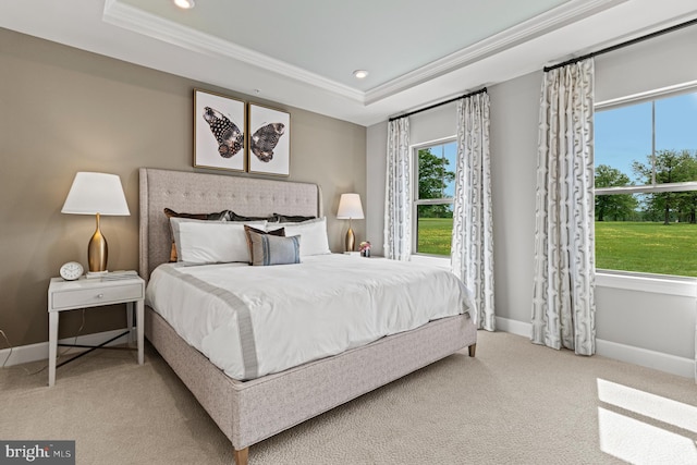 carpeted bedroom with multiple windows, a tray ceiling, and crown molding