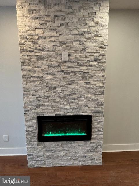 room details featuring wood-type flooring and a stone fireplace