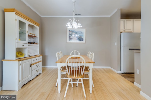 dining area featuring ornamental molding, a chandelier, and light hardwood / wood-style floors