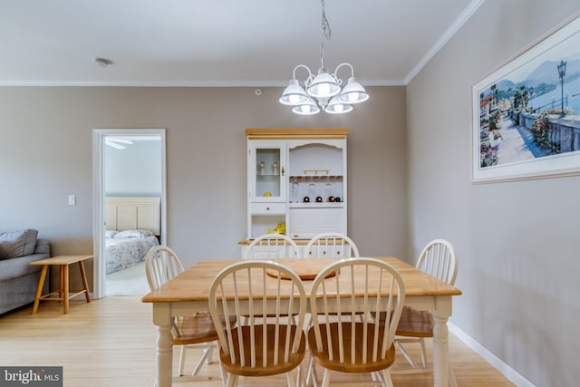 dining room with crown molding, an inviting chandelier, and light hardwood / wood-style flooring