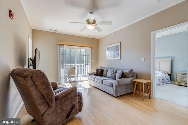 living room with ornamental molding, ceiling fan, and light wood-type flooring