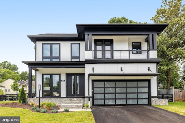 view of front of house with driveway, fence, a balcony, and stucco siding