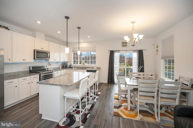 kitchen featuring appliances with stainless steel finishes, light stone countertops, a kitchen island, and white cabinets