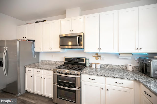 kitchen featuring light stone counters, appliances with stainless steel finishes, dark hardwood / wood-style flooring, and white cabinets