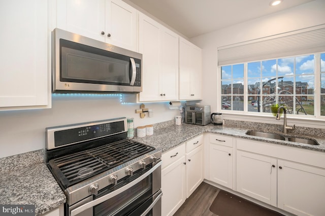 kitchen with light stone countertops, stainless steel appliances, and sink