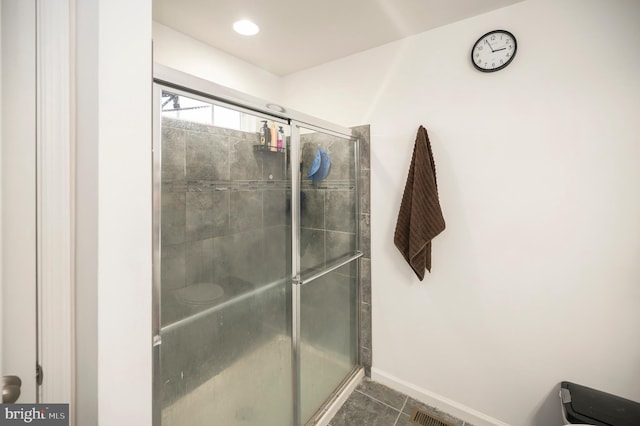 bathroom with an enclosed shower and tile patterned floors