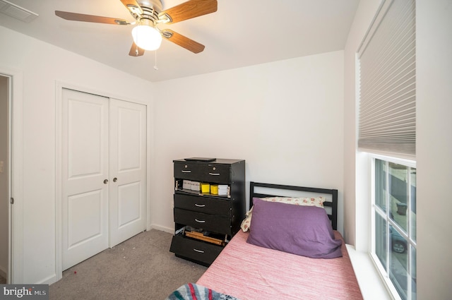 bedroom featuring light colored carpet, ceiling fan, and a closet