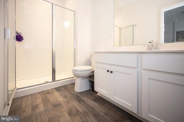 bathroom with wood-type flooring, toilet, an enclosed shower, and vanity