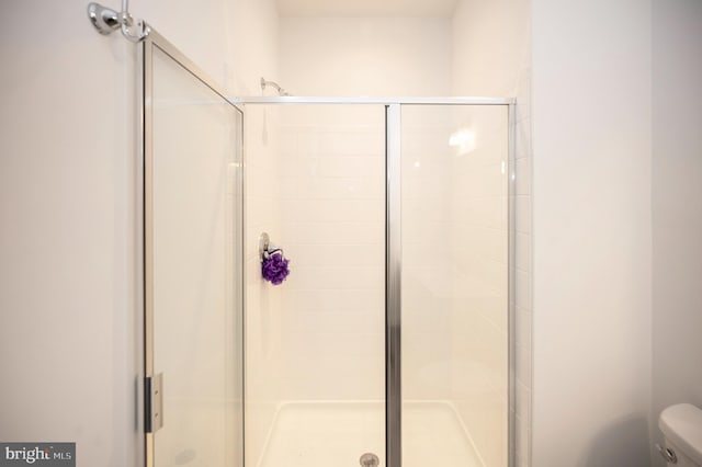 bathroom with a shower with door and toilet