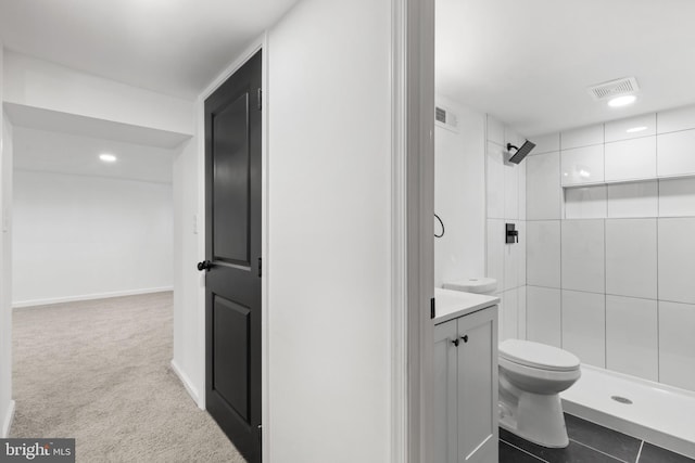 bathroom featuring vanity, toilet, and a tile shower