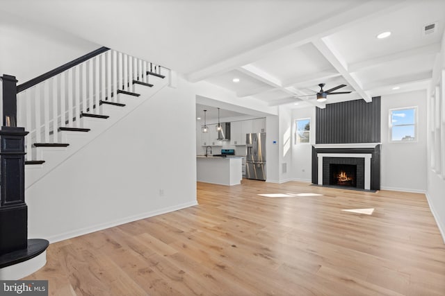 unfurnished living room with beamed ceiling, ceiling fan, coffered ceiling, and light hardwood / wood-style floors