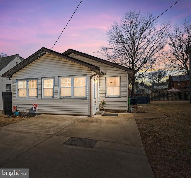 back of house at dusk featuring fence and a yard