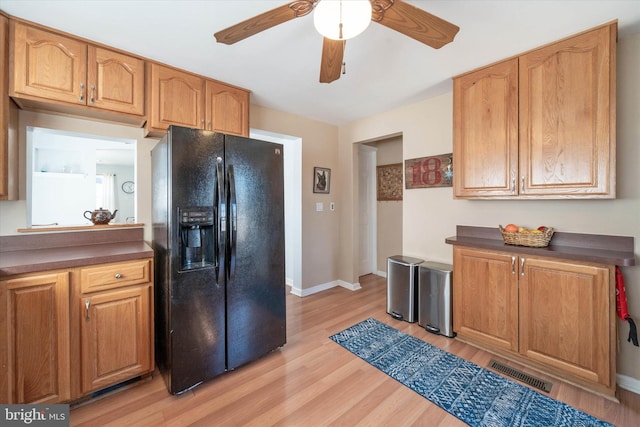 kitchen with dark countertops, visible vents, light wood-style flooring, and black fridge