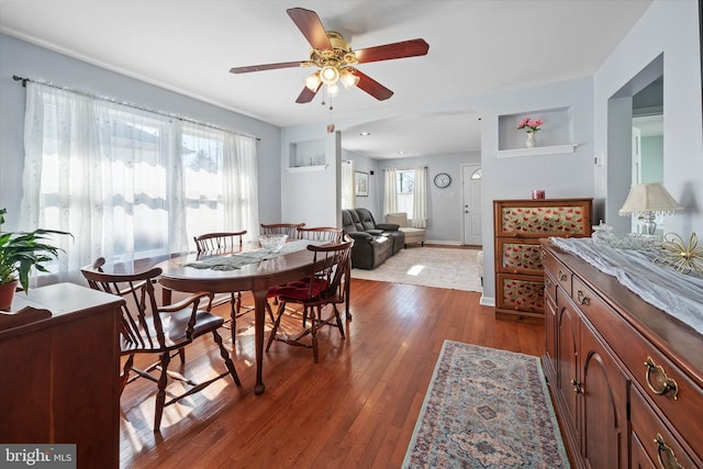 dining area featuring dark wood finished floors, a ceiling fan, and baseboards