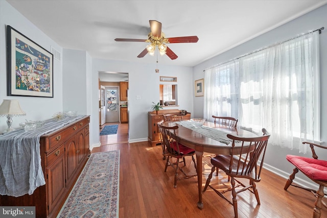 dining room with wood-type flooring, visible vents, baseboards, and a ceiling fan