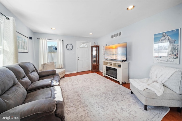 living area featuring recessed lighting, wood finished floors, visible vents, baseboards, and a glass covered fireplace