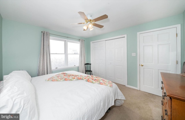 bedroom featuring a ceiling fan, a closet, light carpet, and baseboards