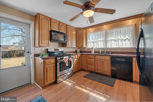 kitchen with black appliances, a sink, light wood-style flooring, and a ceiling fan