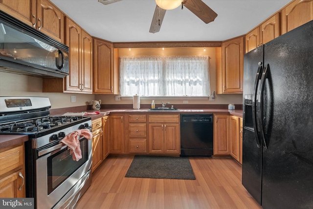 kitchen featuring black appliances, light wood-style flooring, ceiling fan, and a sink