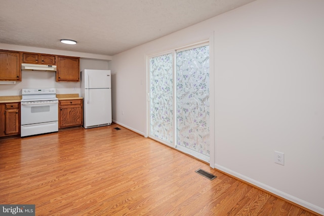 kitchen with white appliances, light hardwood / wood-style flooring, and a textured ceiling