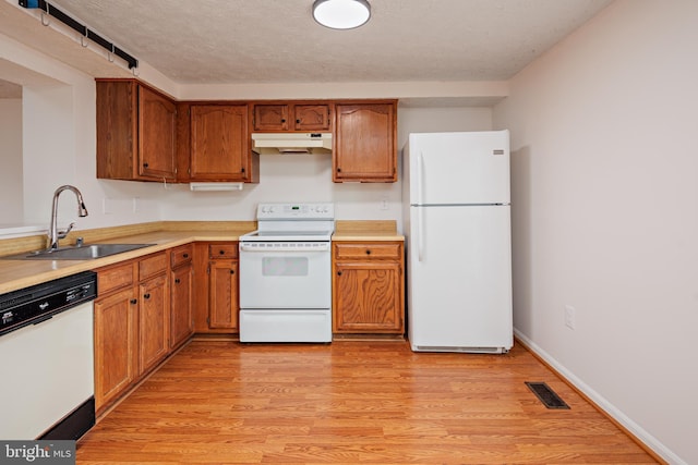 kitchen with white appliances, light hardwood / wood-style floors, sink, and a textured ceiling