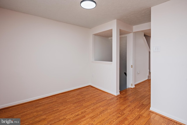 spare room with a textured ceiling and light hardwood / wood-style floors