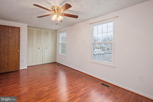 unfurnished bedroom with ceiling fan, dark wood-type flooring, and a textured ceiling