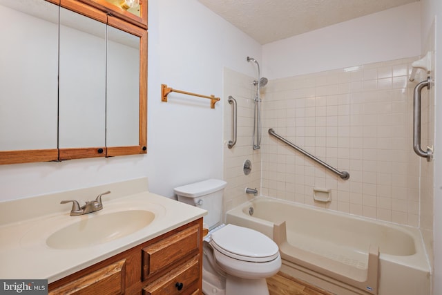 full bathroom with vanity, toilet, tiled shower / bath combo, and a textured ceiling