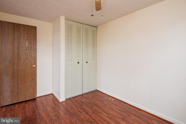 unfurnished bedroom with ceiling fan, dark hardwood / wood-style floors, a textured ceiling, and a closet